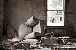 chambre de maison abandonnée avec fauteuil renversé et mobilier cassé