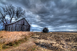 barns in field during storm with clouds in HDR photo