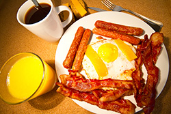 breakfast with coffee, orange juice, eggs, bacon, sausages