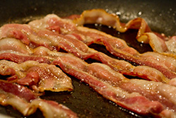 frying bacon in pan for breakfast