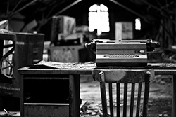 typewriter on desk with chair in office in black and white photo