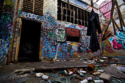 dirty coat hanging in abandoned factory with graffiti