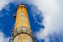 factory chimney to cloudy sky with metallic stairs