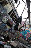 low-angle picture of coat hanging in dirty place with graffiti