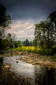 countryside river HDR with rocks beside fields during storm