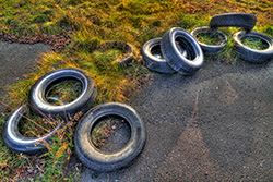 pneus usés sur route, posés sur le sol, asphalte et herbe