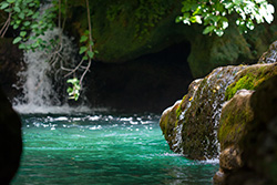 turquoise river with waterfall, moss on rocks