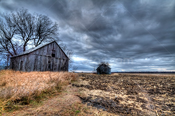 Barns in field during storm with clouds in HDR photo