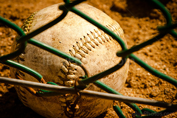 Baseball behind fence on the ground