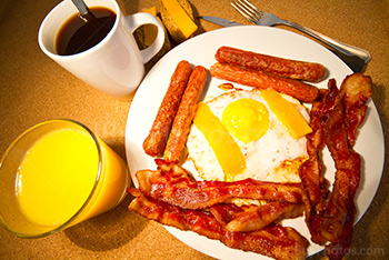 Breakfast with coffee, orange juice, eggs, bacon, sausages