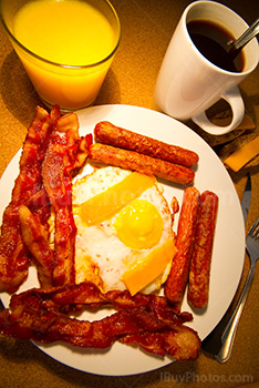 Petit déjeuner avec oeufs, bacon, saucisses, café et jus d'orange