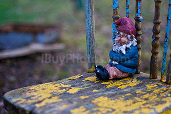 Garden gnome seating on old chair close-up