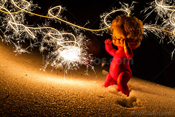 Winter party doll on snow, lighted by burning sparkler, lightpainting