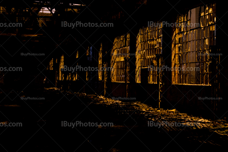 Broken windows and glass in abandoned building with light from street