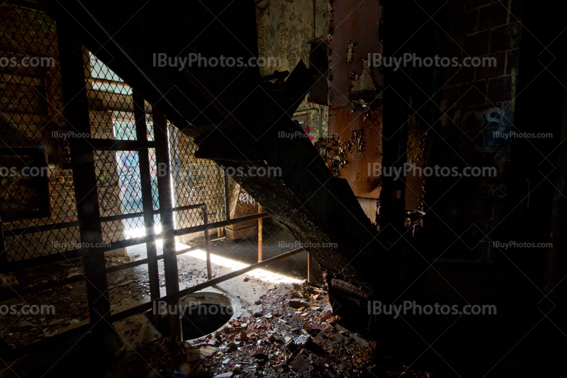 Abandoned factory interior with light from doorway and metal structures