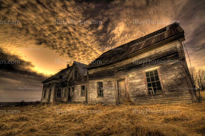 Vieille mainson abandonnée dans un champ avec ciel nuageux, sur photo couleur HDR