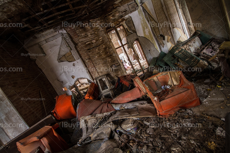 Old armchairs and dirty objects in abandoned house interior