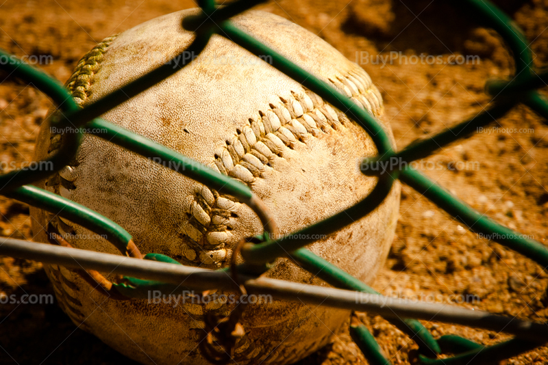 Baseball behind fence on the ground