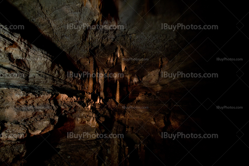 Dark cave with light on stalagmites and stalactites