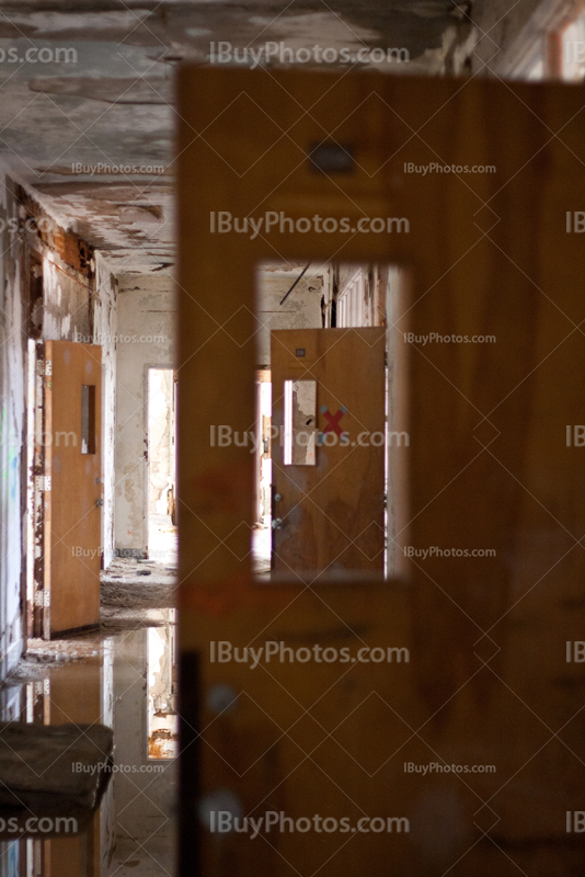 Opened doors in abandoned corridor with water on floor