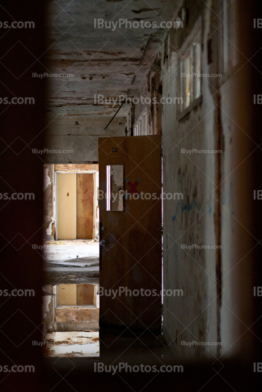 Abandoned school corridor with opened door and water on floor