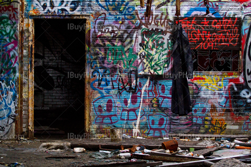 Dirty coat hanging in demolished house, with doorway and graffiti