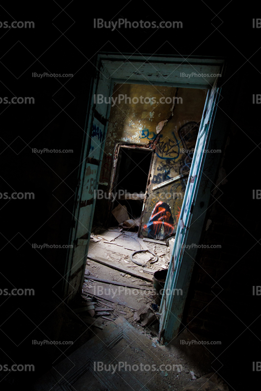 Lumière dans encadrement de porte dans maison abandonnée avec salle sombre