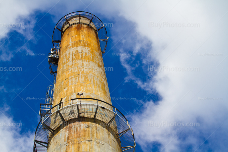 Factory chimney to cloudy sky with metallic stairs