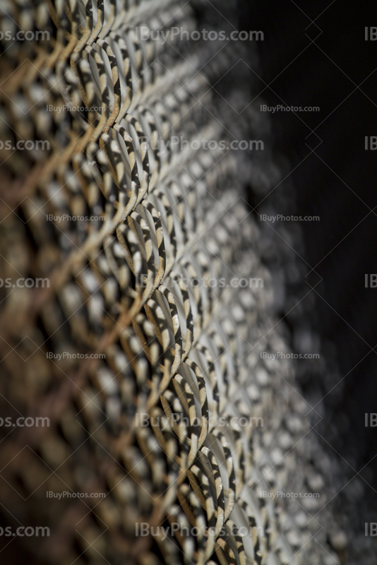 Inclined rusty metal fence, chain link perspective