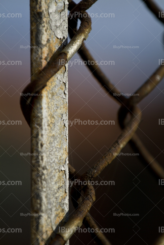 Rusty chain link fence attached to metal pole