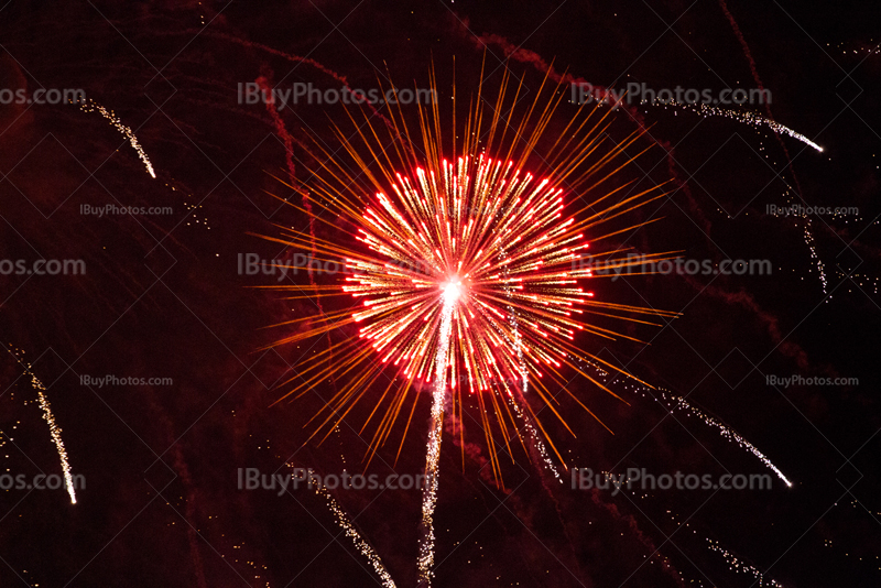 Bright red firework explosion with rocket trail and glitter