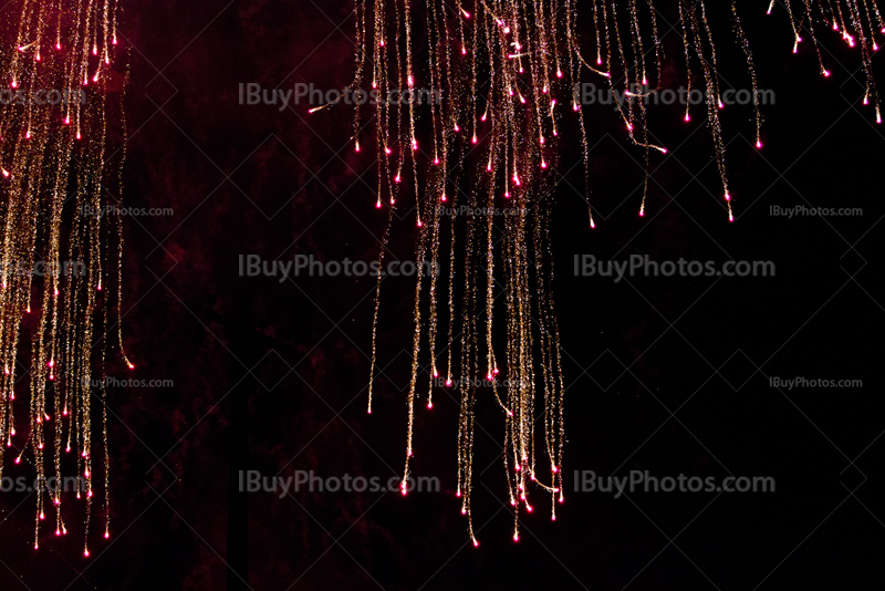 Cendres rouges incandescentes de feux d'artifices sur ciel noir