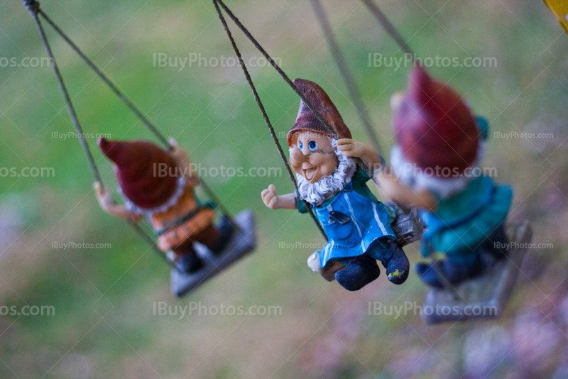 Garden gnomes on swing, with red hoods