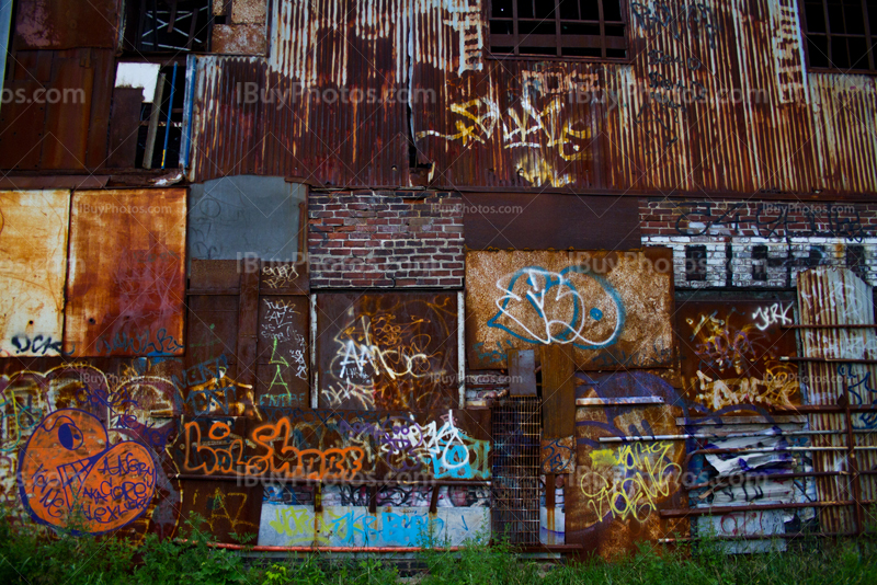 Rusty plates and corrugated iron wall with graffiti