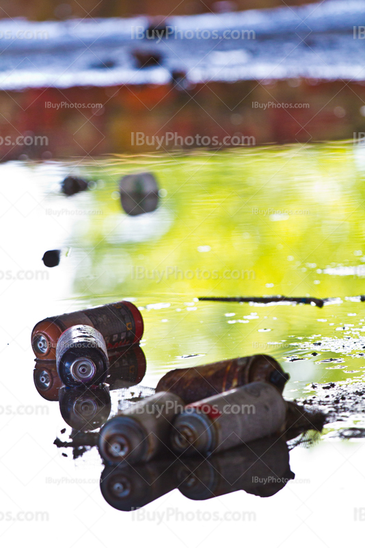 Graffiti spray cans in puddle of water