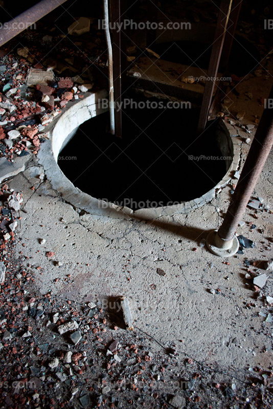 Manhole with metal stairs and fragments on floor