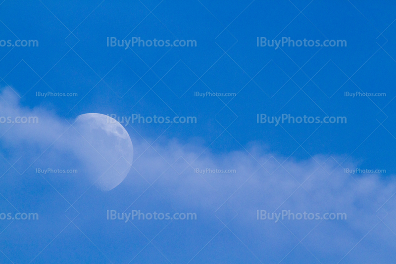 Moon hidden by clouds in blue sky