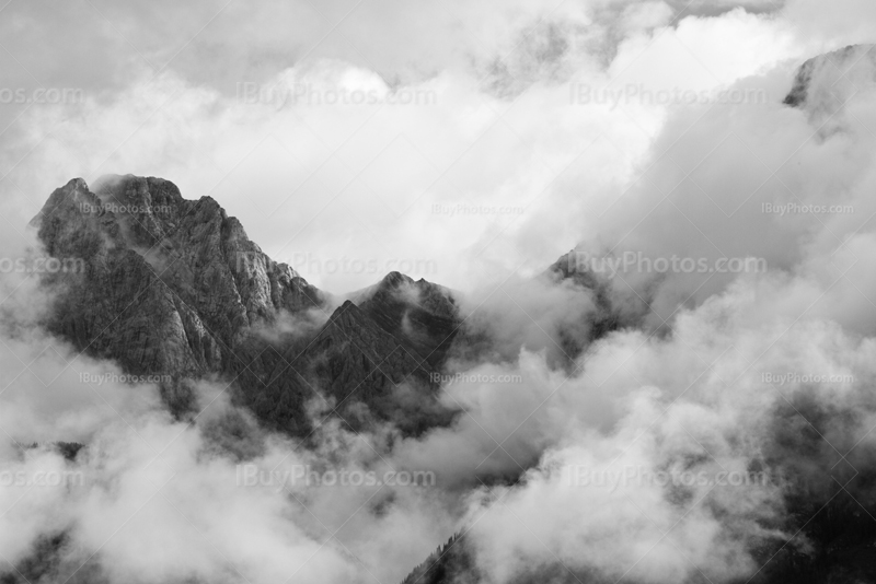 Mountain summit in clouds in black and white photo in Rockies
