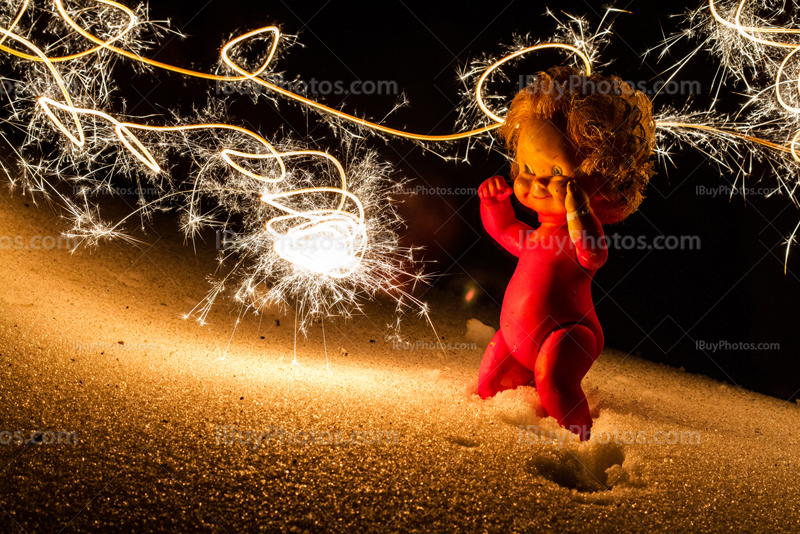 Winter party doll on snow, lighted by burning sparkler, lightpainting