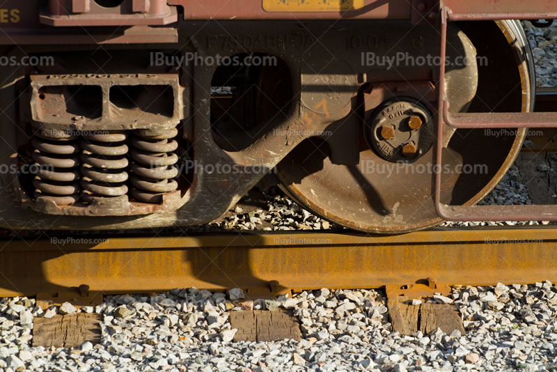 Rusty wagon wheel on rails and gravels