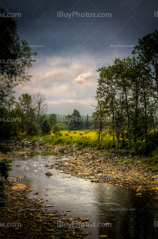 Rivière en campagne à côté d'un champ pendant orage en HDR