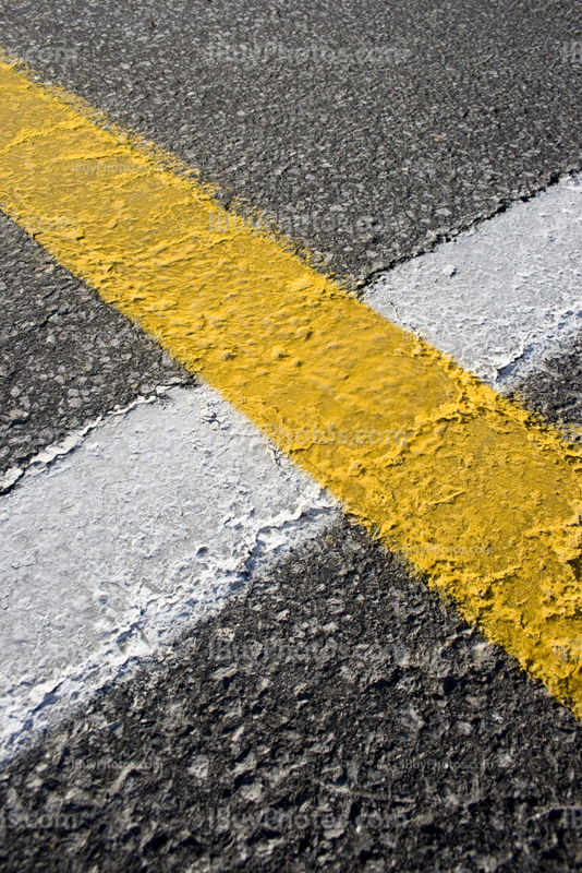 Lignes blanches et jaunes sur route asphaltée