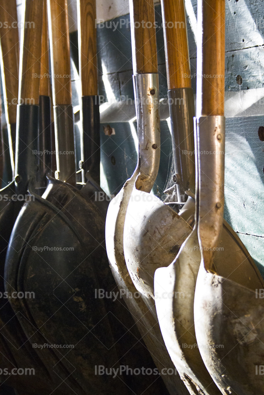 Shovels hang on wall with sunlight