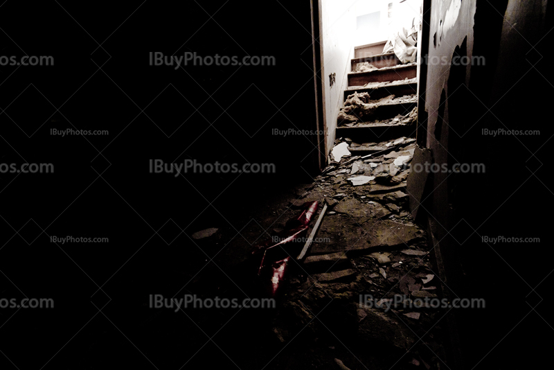 Escaliers lumineux dans salle sombre de maison abandonnée