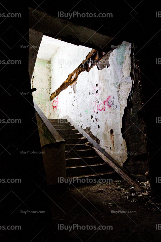 Lumière en haut d'escaliers sombres dans bâtiment délabré