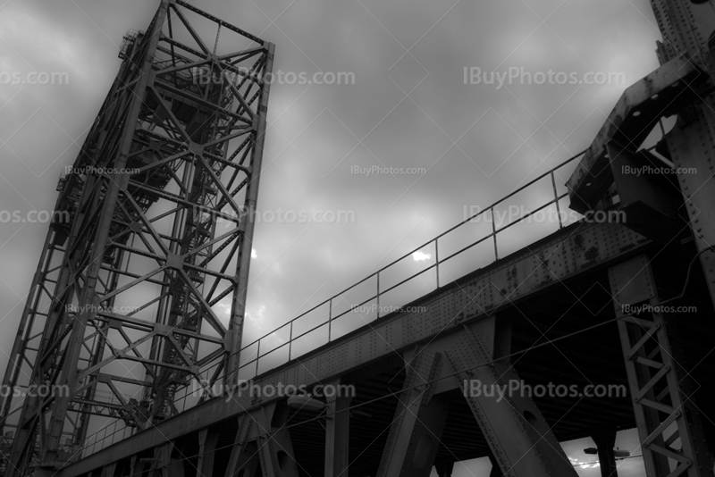 Metal tower structure with steel beams bridge with cloudy sky