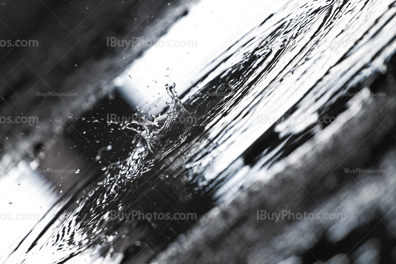 éclaboussure dans flaque d'eau sur sol en béton