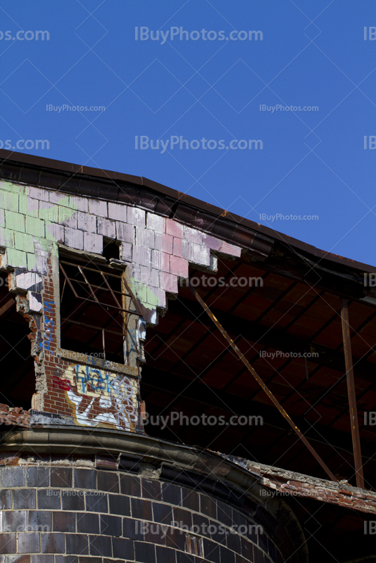 Broken window and crumbling wall with graffiti on top of factory silo