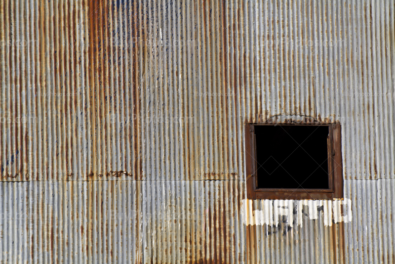 Old window on rusty corrugated iron plates