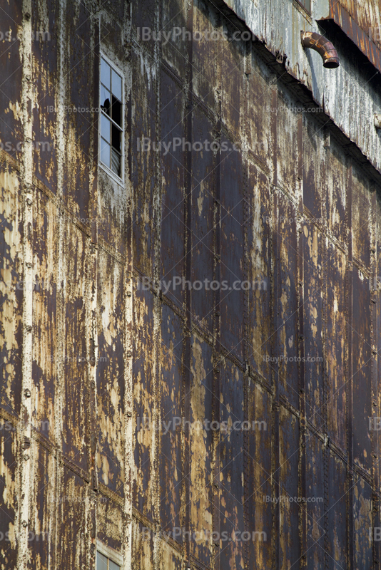 Broken windows on old factory wall with rusty plates